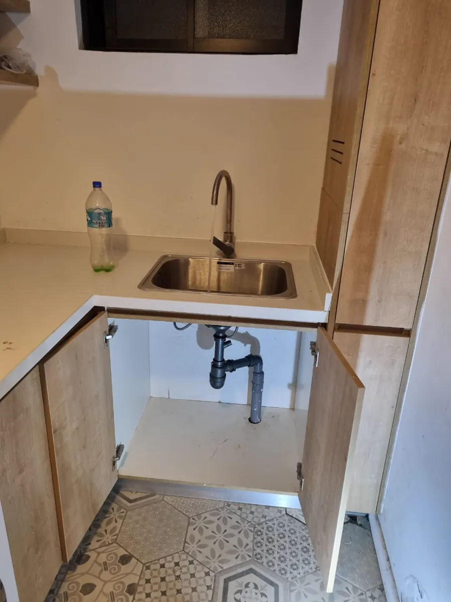 Mueble del lavaplatos abierto mostrando el sifón